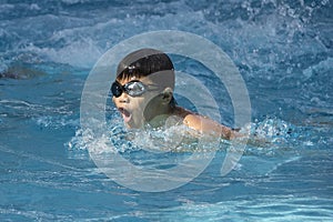 Healthy boy butterfly style swims in swimming pool