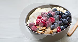 Healthy breakfast with acai bowl, raspberries, blueberries, almonds, bananans , healthy granola or muesli bowl with fresh berries