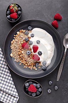 Healthy breakfast with baked granola and greek yogurt. Assorted fresh berries. Vertical photo