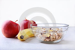 Healthy breakfast with banana, apple and Fresh granola, muesli in bowl on textile background. Top view.