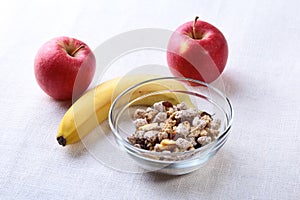 Healthy breakfast with banana, apple and Fresh granola, muesli in bowl on textile background. Top view.