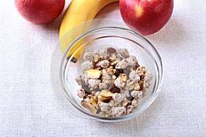 Healthy breakfast with banana, apple and Fresh granola, muesli in bowl on textile background. Top view.