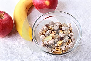 Healthy breakfast with banana, apple and Fresh granola, muesli in bowl on textile background. Top view.