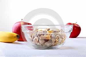 Healthy breakfast with banana, apple and Fresh granola, muesli in bowl on textile background. Top view.