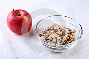 Healthy breakfast with banana, apple and Fresh granola, muesli in bowl on textile background. Top view.