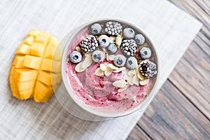 Healthy breakfast berry smoothie bowl topped with banana, granola