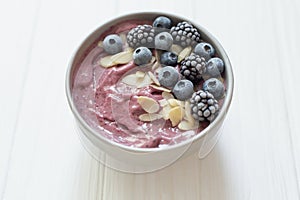 Healthy breakfast berry smoothie bowl topped with banana, granola, Blueberries and chia seeds with copy space