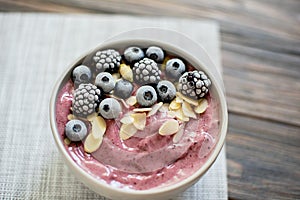 Healthy breakfast berry smoothie bowl topped with banana, granola, Blueberries and chia seeds with copy space