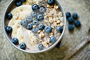 Healthy breakfast berry smoothie bowl topped with banana, granola, Blueberries and chia seeds with copy space