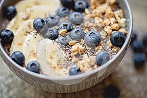 Healthy breakfast berry smoothie bowl topped with banana, granola, Blueberries and chia seeds with copy space