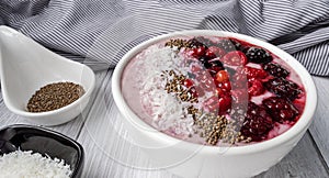 Healthy breakfast berry smoothie bowl topped with Blueberries, blackberries, chia seeds, raspberry and grounded coconut flakes.