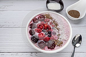 Healthy breakfast berry smoothie bowl topped with Blueberries, blackberries, chia seeds, raspberry and grounded coconut flakes.