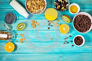 Healthy breakfast with bowl of cereal, orange juice, granola, milk, jam and fruits on blue wood background. Balanced diet.