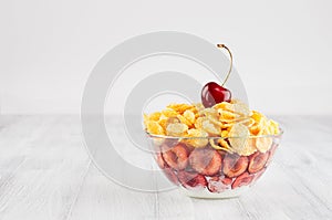 Healthy breakfast in bowl with golden corn flakes decorated cherry on white wood board. Decorative border with copy space.