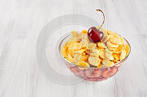 Healthy breakfast in bowl with golden corn flakes, ripe slice cherry on white wood board. Decorative border with copy space.