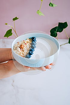 Healthy breakfast bowl with muesli and yogurt in woman hands