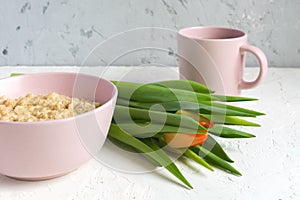 Healthy breakfast. Bowl of oatmeal and cup of black tea. served with fresh blooming tulip. Morning romantique atmosphere