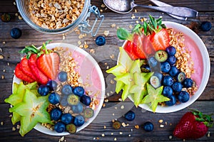 Healthy breakfast bowl: raspberry smoothies with granola, blueberries, strawberries and carambola