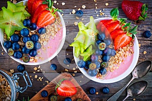 Healthy breakfast bowl: raspberry smoothies with granola, blueberries, strawberries and carambola