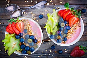 Healthy breakfast bowl: raspberry smoothies with granola, blueberries, strawberries and carambola