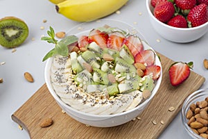 Healthy breakfast bowl: smoothie with banana, strawberries, kiwi, granola, almonds and Chia seeds.