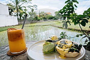 Healthy Breakfast with Bread Toast and Poached Egg with spinach, avocado on wooden table with rice field view. Orange