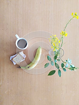 A healthy breakfast, bread, turkey, banana and coffee with flowers on a spring or summer day