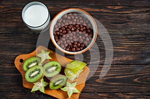 Healthy breakfast - cereal chocolate balls, milk and fruit on wood background