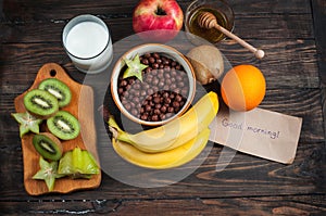 Healthy breakfast - cereal chocolate balls, milk and fruit on wood background