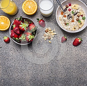 Healthy breakfast cereal with dried fruits, fresh orange juice, a plate of strawberries on wooden rustic background top view borde photo