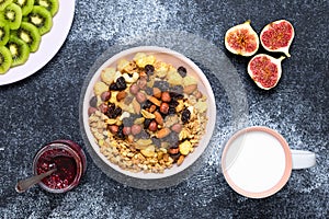 Healthy breakfast cereal, muesli with raisins and nuts. A bowl of dry granola with milk on a dark background. Snack food of rolled