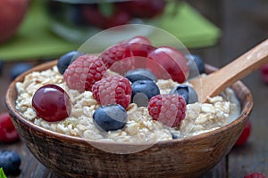 Healthy breakfast cereal oat flakes in bowl on wooden table