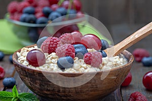 Healthy breakfast cereal oat flakes in wooden bowl with wooden spoon