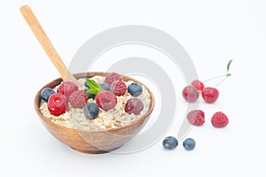 Healthy breakfast cereal oat flakes in wooden bowl with wooden spoon