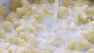 Healthy breakfast of cheerios whole grain cereals with milk, close up. Milk pouring into bowl. Pouring milk into a bowl
