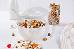 Healthy breakfast concept. Baked granola in white ceramic bowl and glass jar