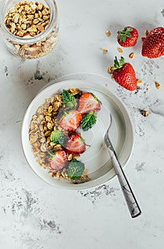 Healthy breakfast concept. Bowl with granola, yogurt and berries on white marble background