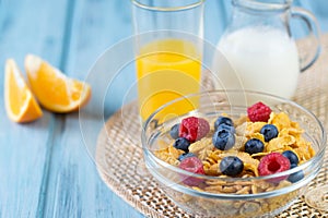 Healthy breakfast concept - cereals with berries, orange juice, orange slices and milk