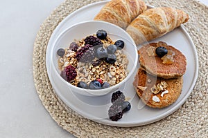 Healthy breakfast concept. Granola with berries, croissants and pancakes