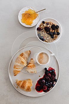 Healthy breakfast concept. Granola with coffee, berries, croissants and orange marmelade.