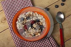 Healthy breakfast concept with oat flakes, nuts, blueberries and raspberries on kitchen towel and rustic wooden background