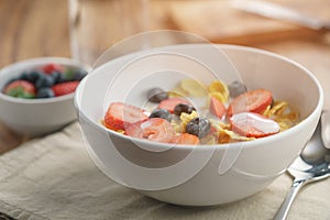 Healthy breakfast with corn flakes and berries in white bowl