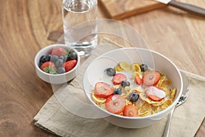 Healthy breakfast with corn flakes and berries in white bowl