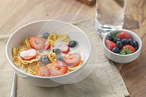 Healthy breakfast with corn flakes and berries in white bowl