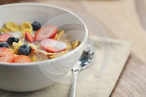 Healthy breakfast with corn flakes and berries in white bowl