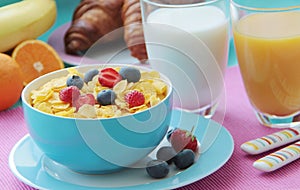 Healthy breakfast with corn flakes, milk, croissants, orange juice and fresh fruits as banana, oranges, strawberries and blueberri