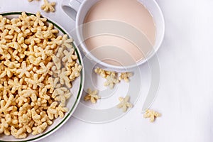 A healthy Breakfast of corn flakes, milk and tea on a white table