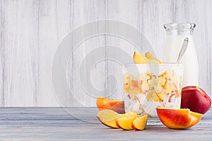 Healthy breakfast with corn flakes, slice peach and milk bottle on white wood board.