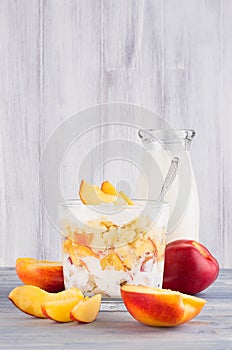 Healthy breakfast with corn flakes, slice peach and milk bottle on white wood board.