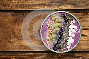 Healthy breakfast with delicious acai smoothie and fruits in bowl on wooden table, top view. Space for text